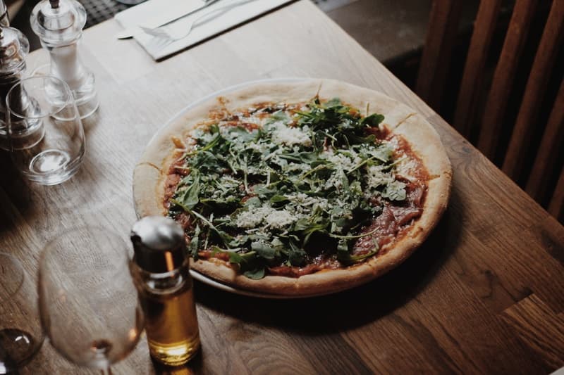 Færdig pizza med frisk rucola og parmesan